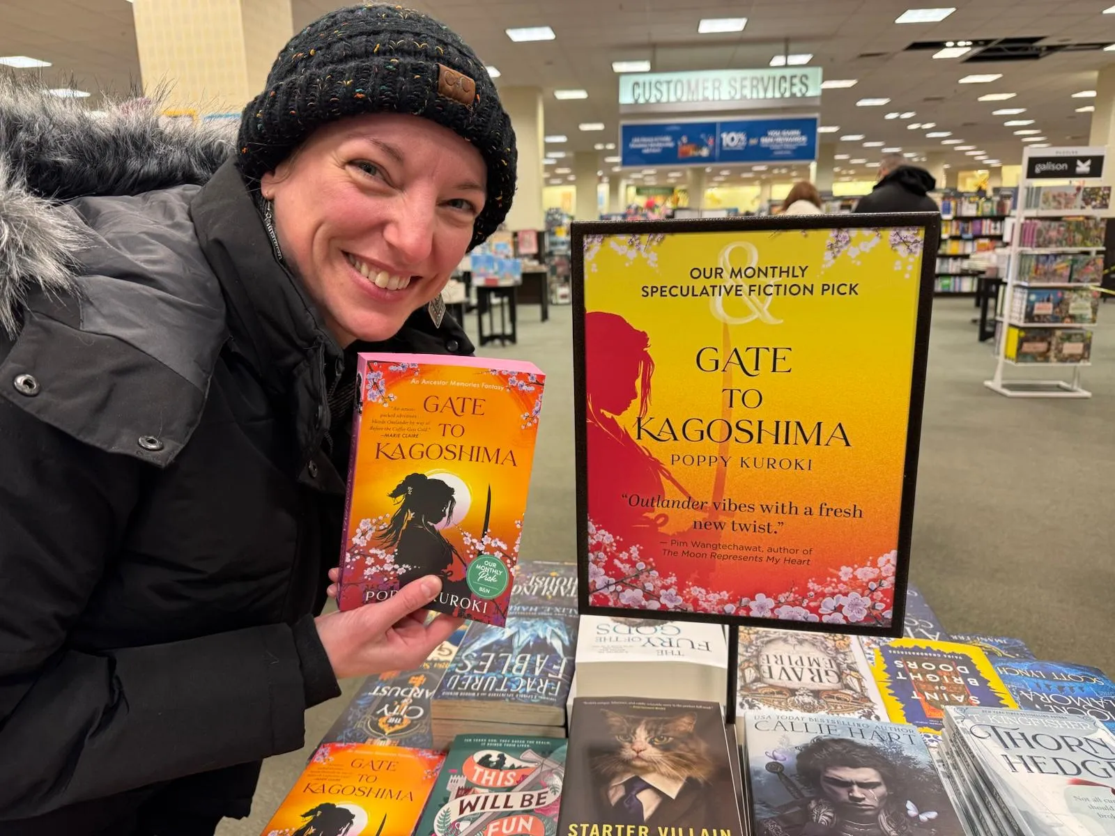 Jessica holding Gate to Kagoshima beside its Barnes & Noble Monthly Speculative Fiction Pick display